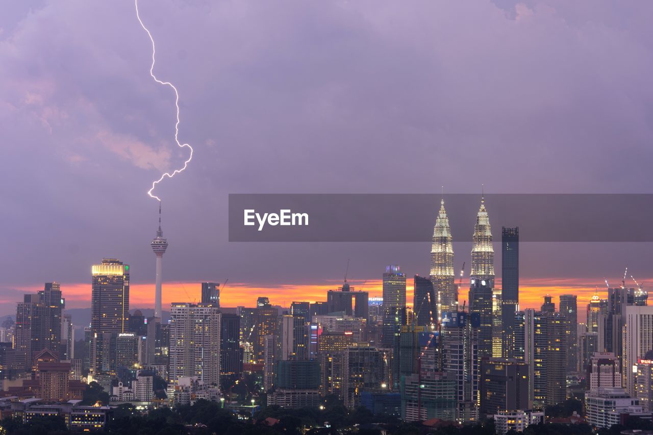 View of thunderstorm over cityscape at dusk