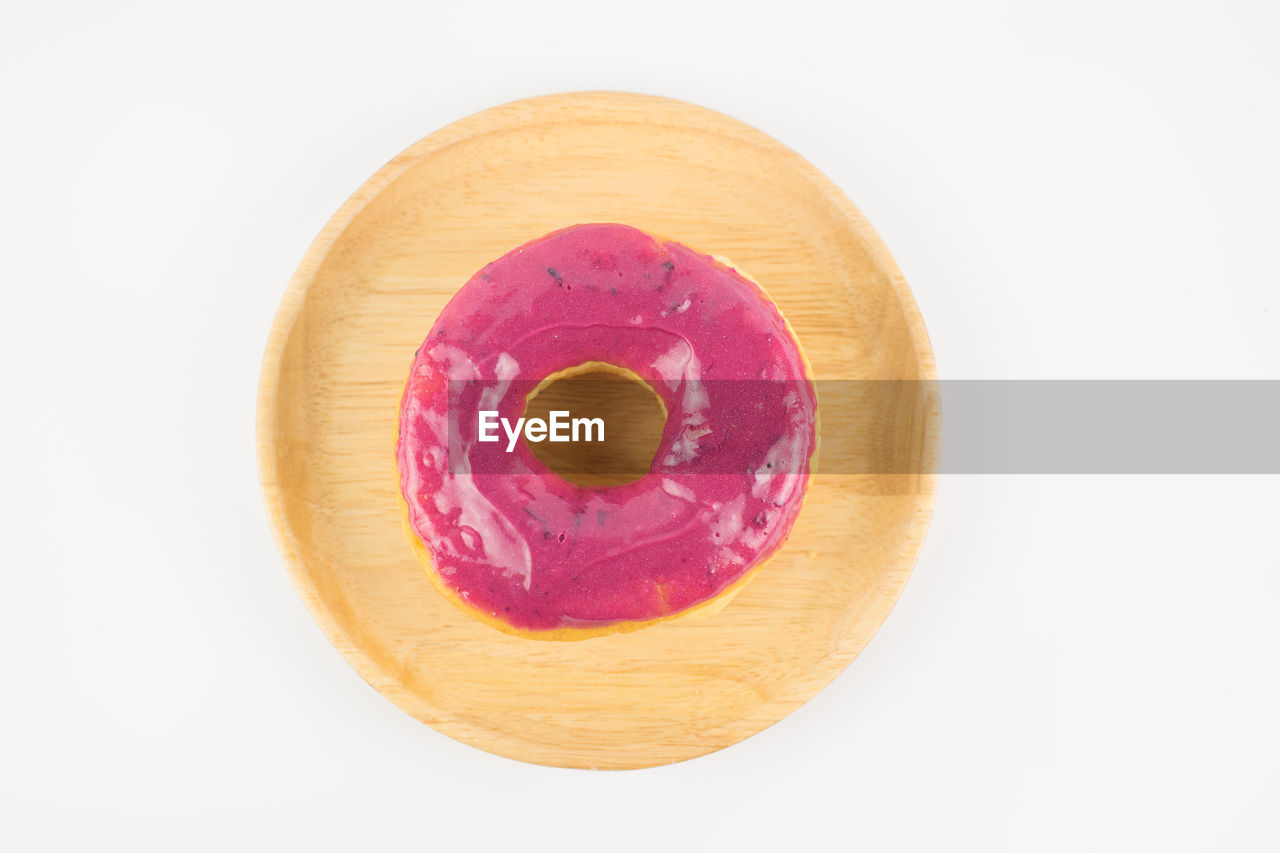 Directly above shot of donut in wooden plate over white background