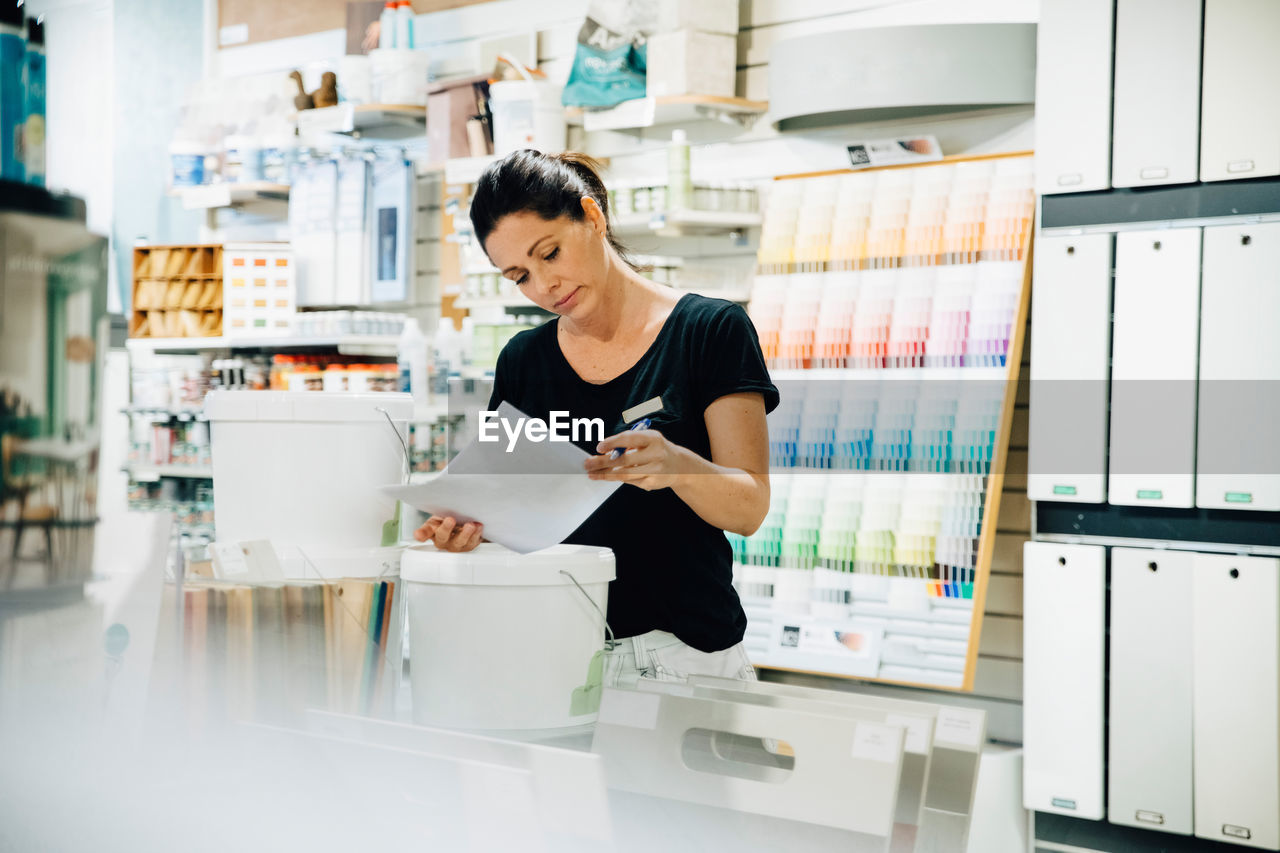 Female employee reading document at hardware store