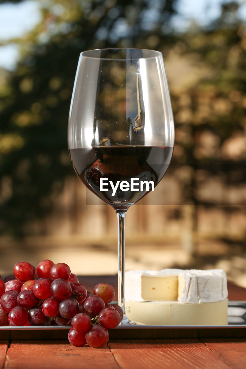 Close-up of wineglass with grapes and cheese on table