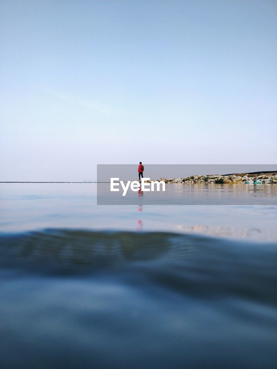 Rear view of man standing on sea shore against sky