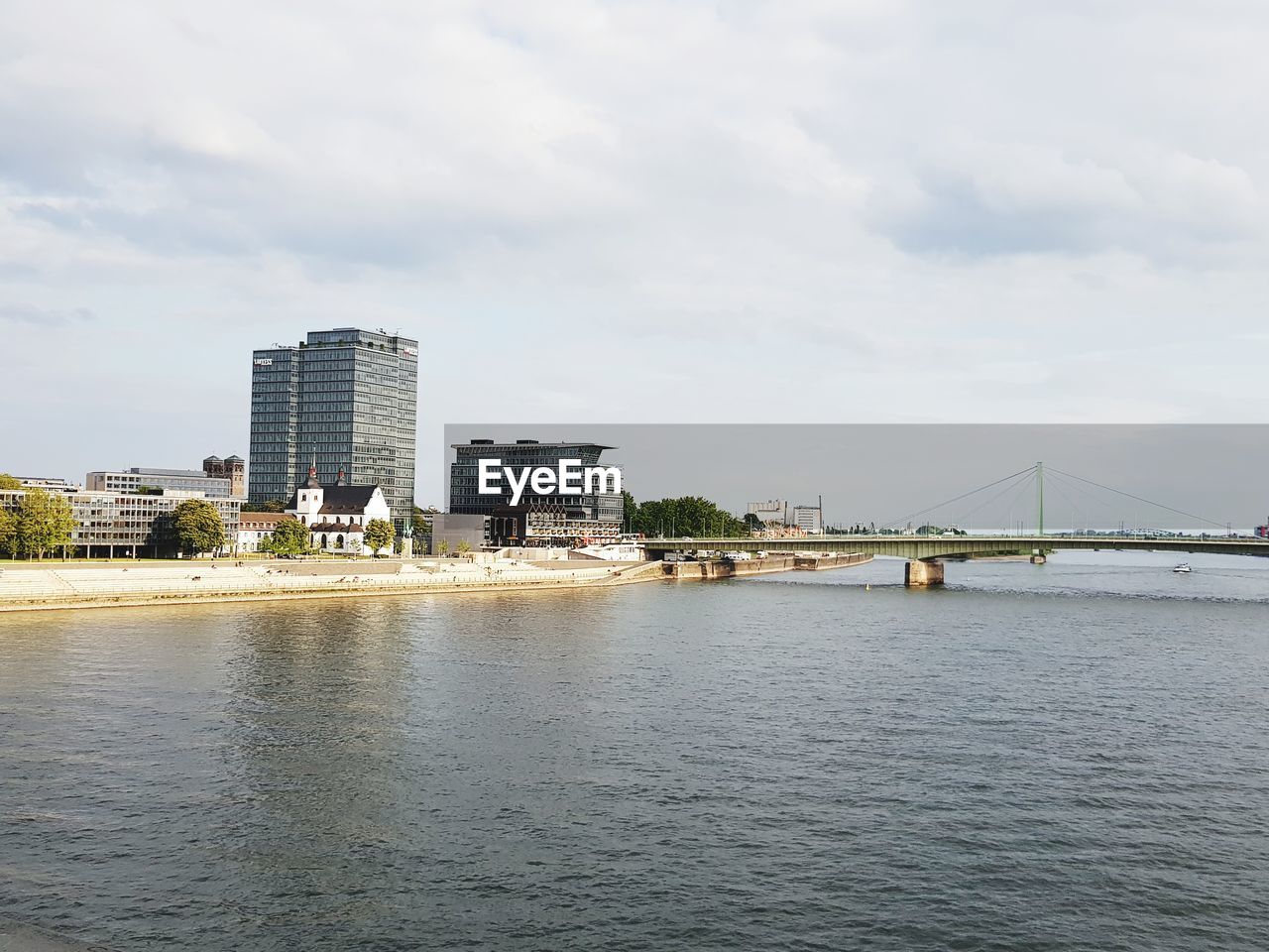 Bridge over river by buildings against sky