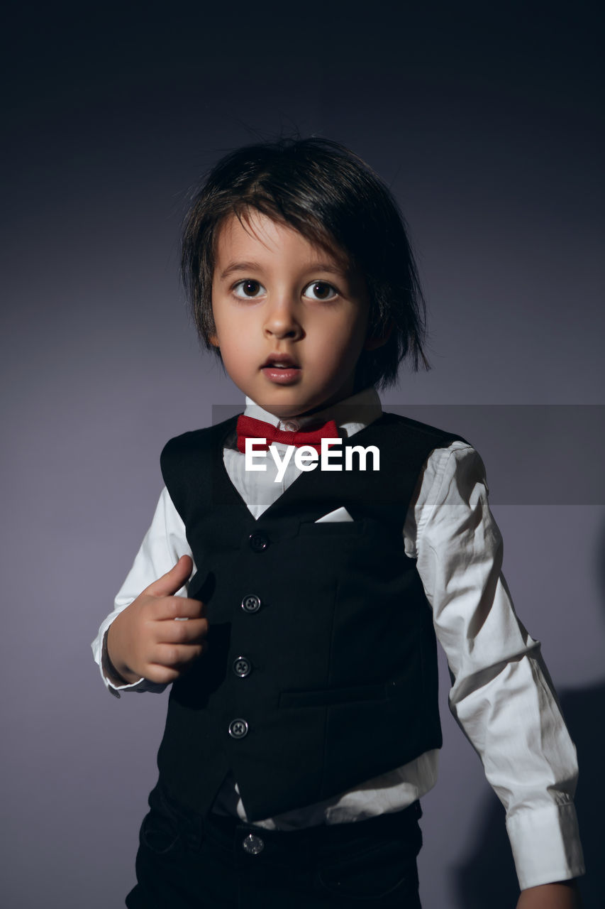 Stylish boy child of four years in the studio on the background in a vest and a red bow tie