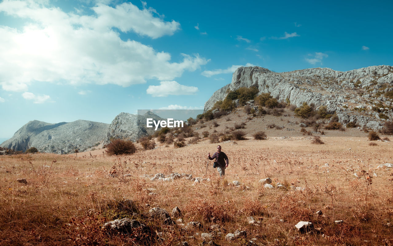 MAN ON FIELD AGAINST MOUNTAINS