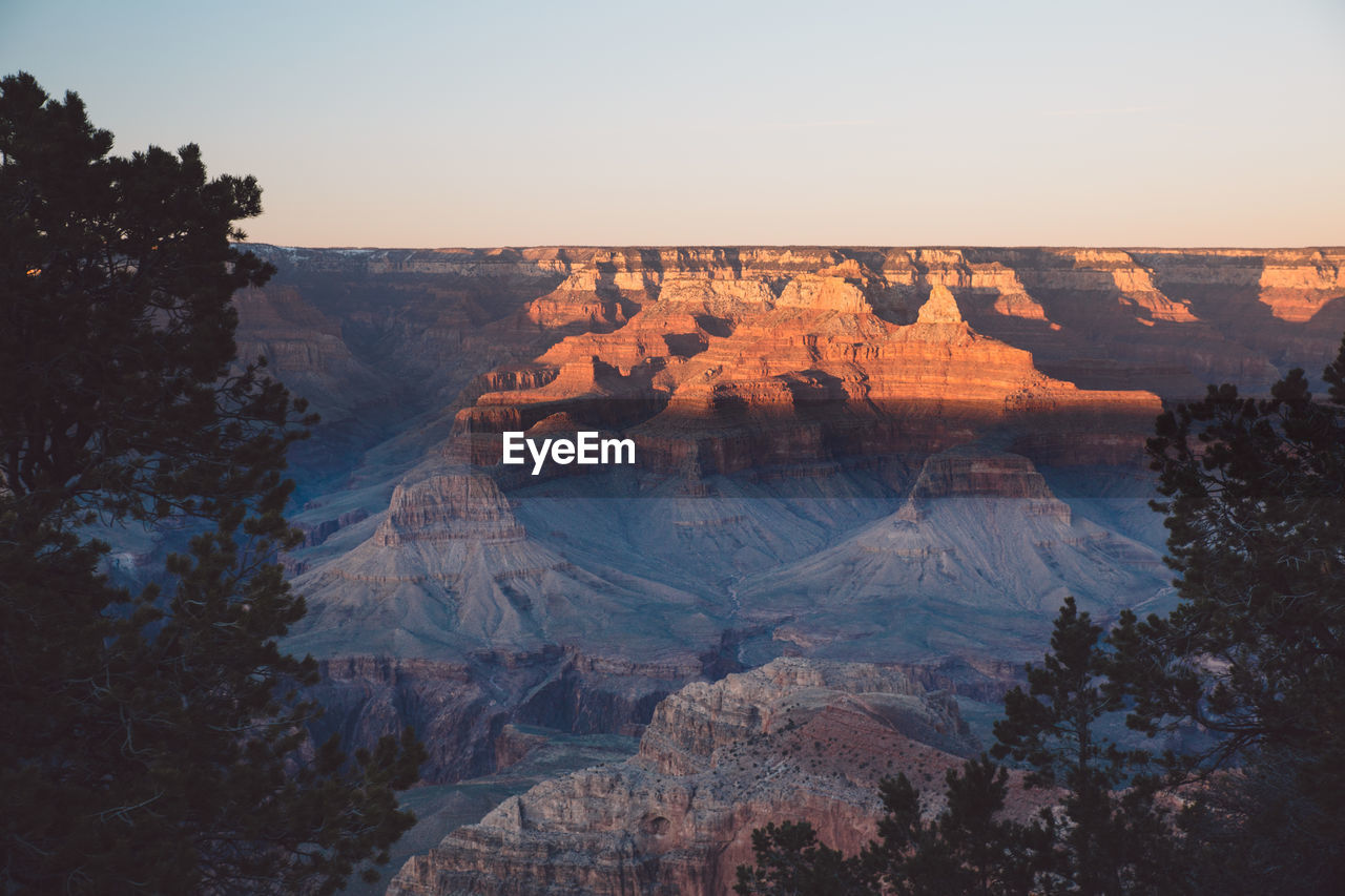 Scenic view of eroded landscape against clear sky during sunset