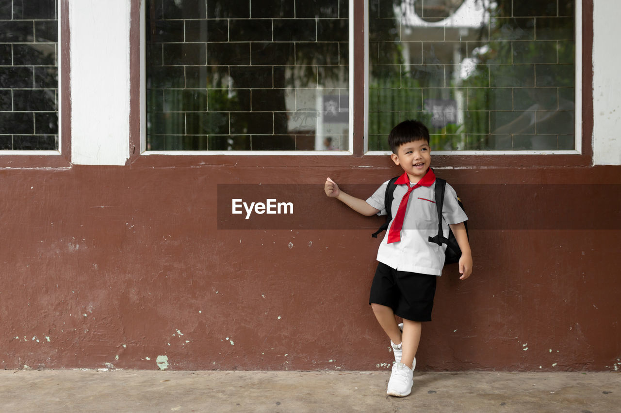 Full length of cute boy standing by school building