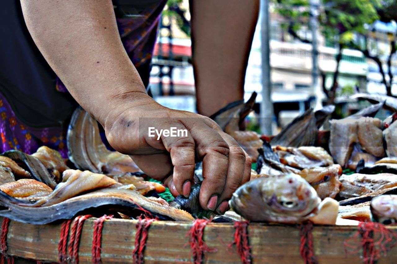 Midsection of woman arranging fish on market stall