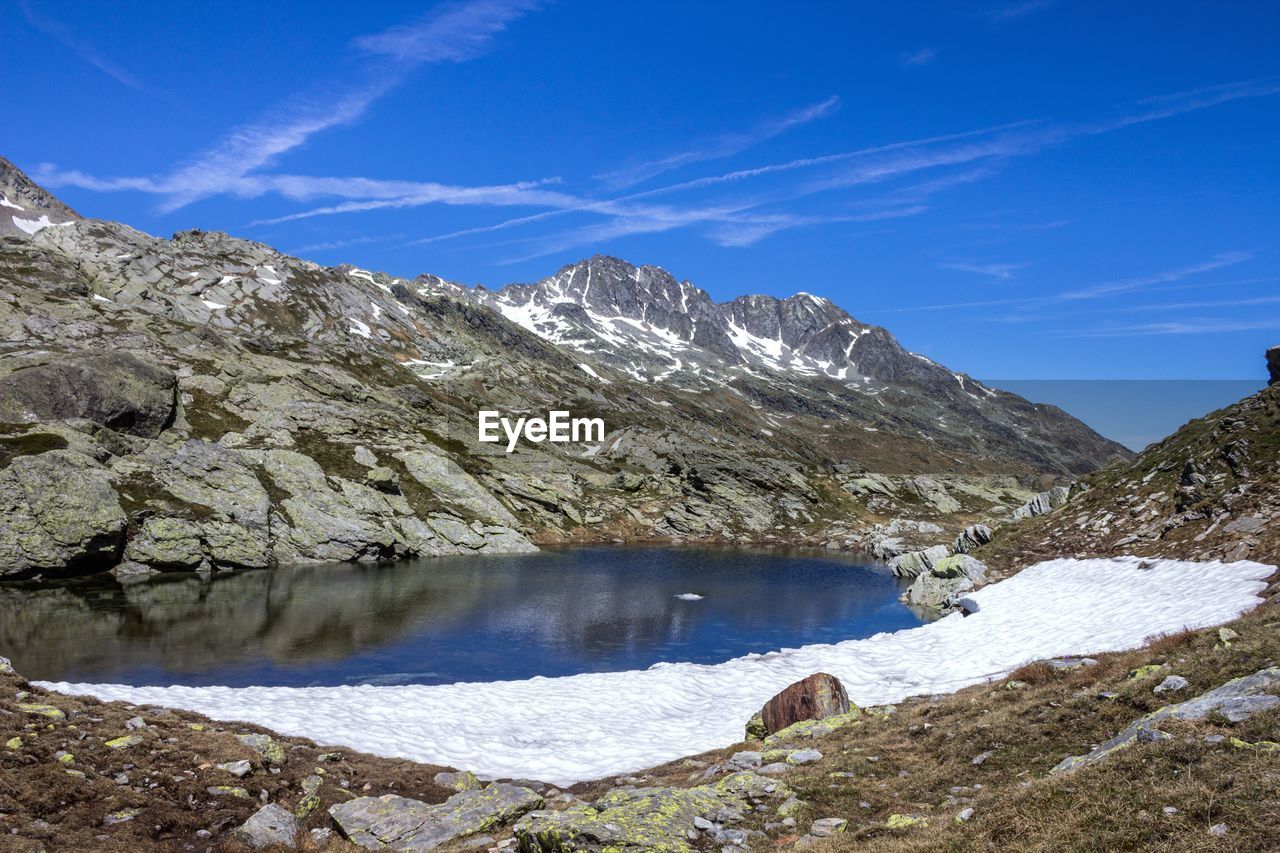 water, scenics - nature, beauty in nature, mountain, sky, cold temperature, nature, tranquil scene, winter, day, snow, tranquility, no people, non-urban scene, environment, rock, landscape, cloud - sky, outdoors, flowing water, snowcapped mountain