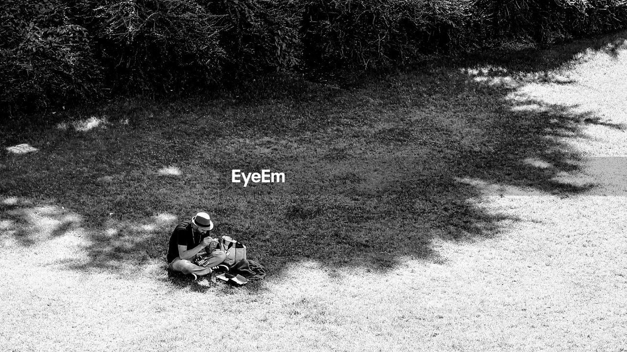 High angle view of man sitting on grassy field by trees