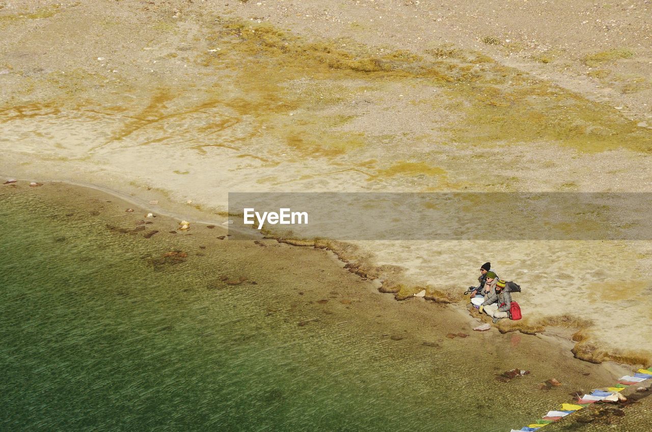 HIGH ANGLE VIEW OF PEOPLE WALKING ON SANDY BEACH