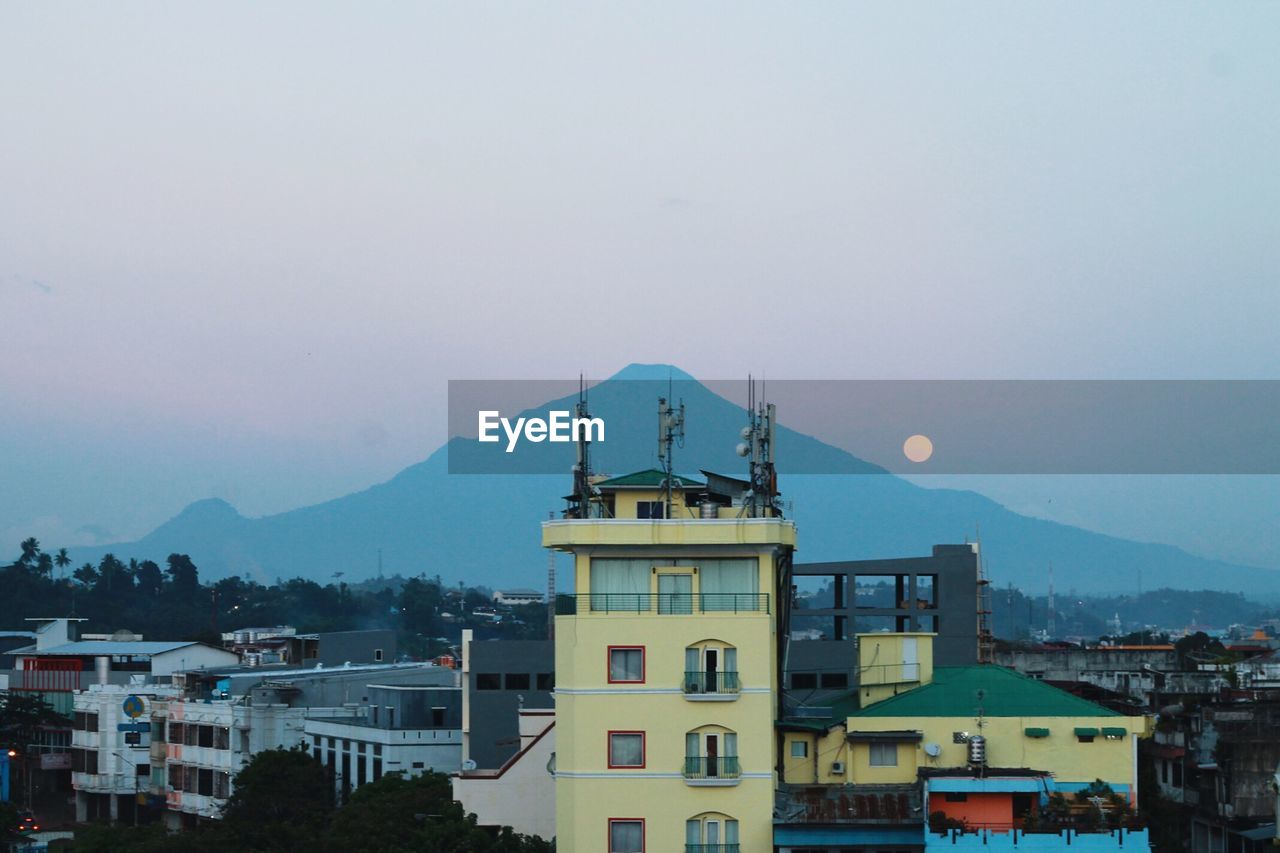 View of town with mountain in background at dusk