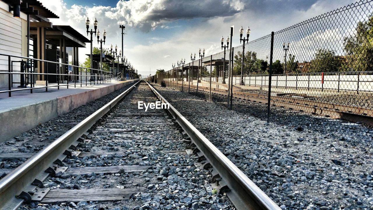 Tracks by railroad station against sky