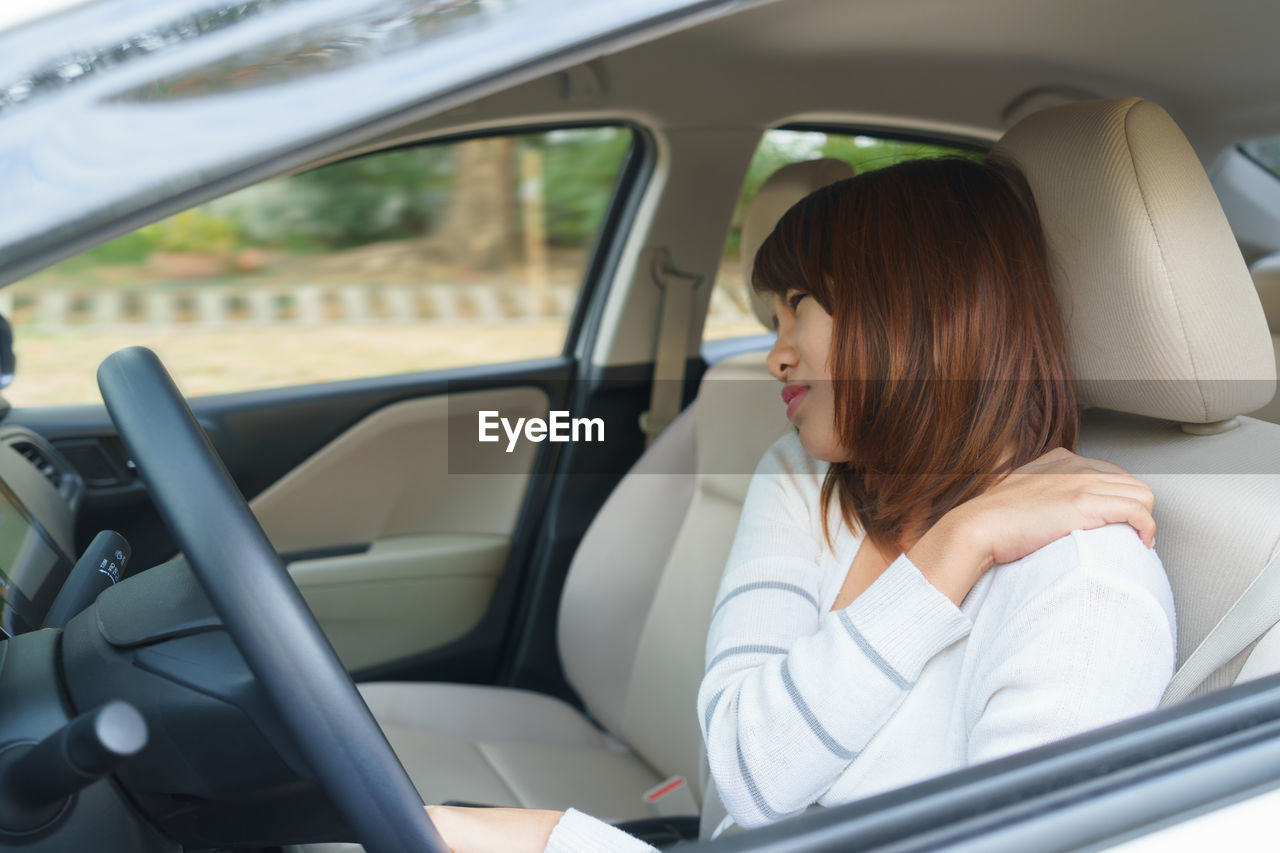 Woman with back pain sitting in car