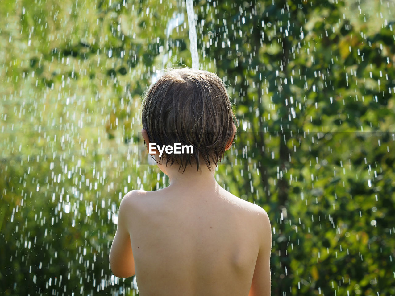 Boy under shower in garden