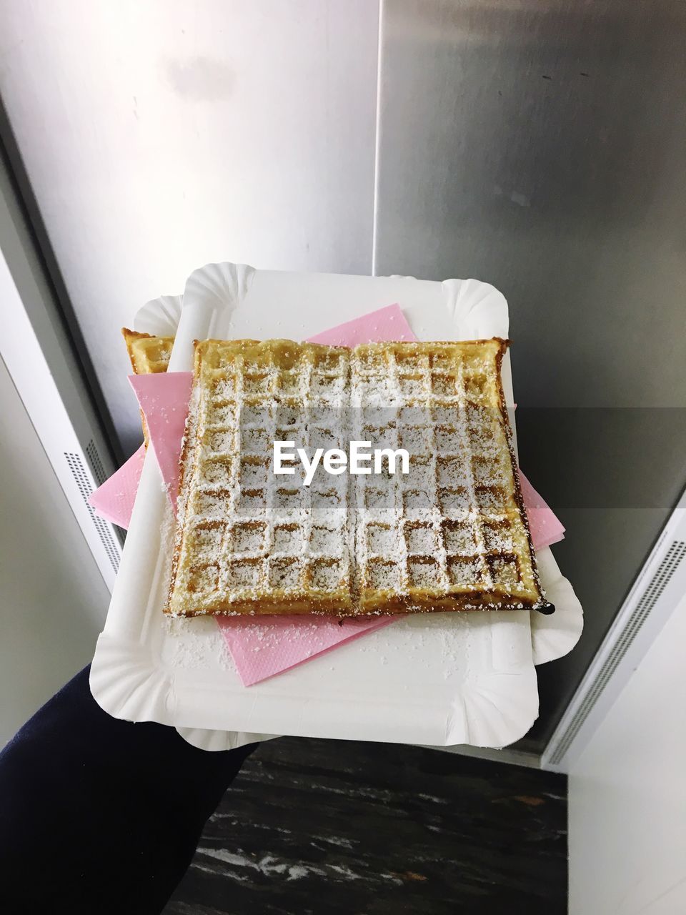 Cropped hand holding plate with waffle in elevator