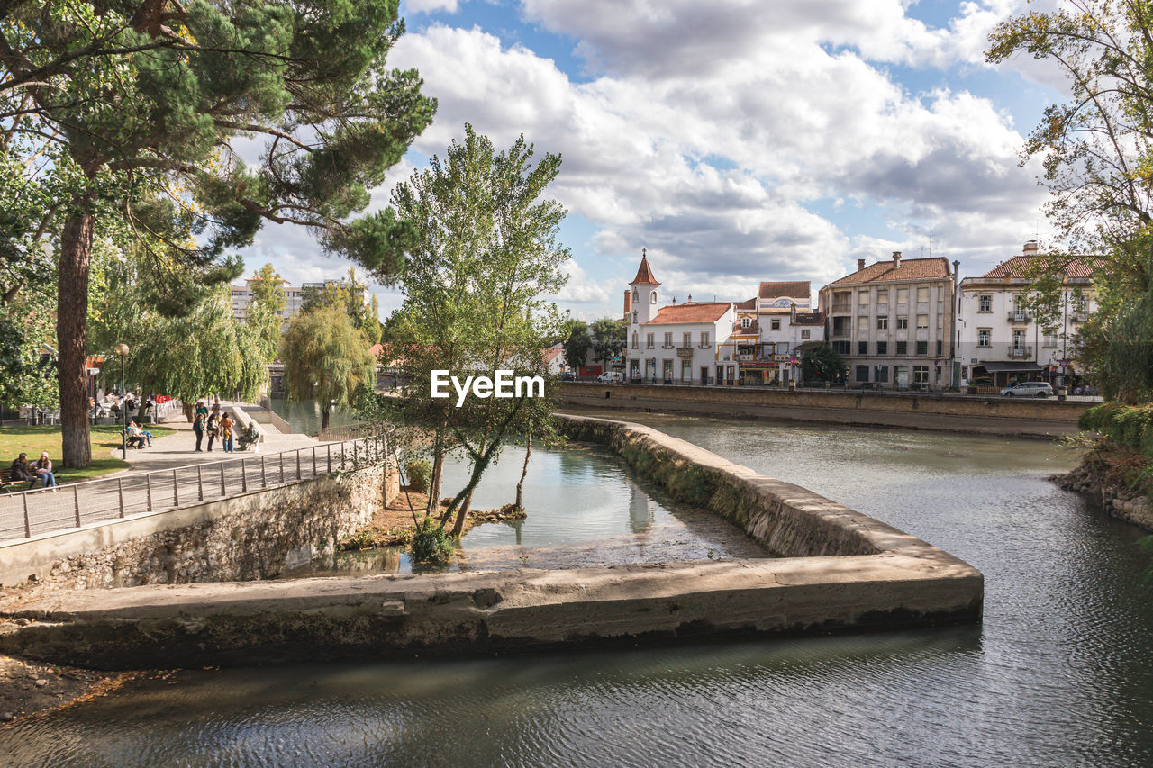 Bridge over river by buildings against sky