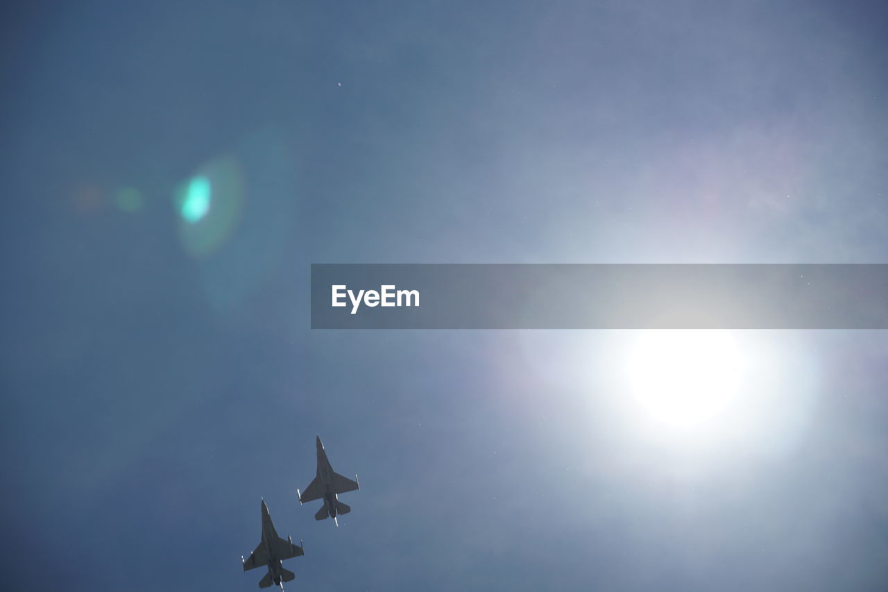 Low angle view of fighter planes flying against sky during sunny day