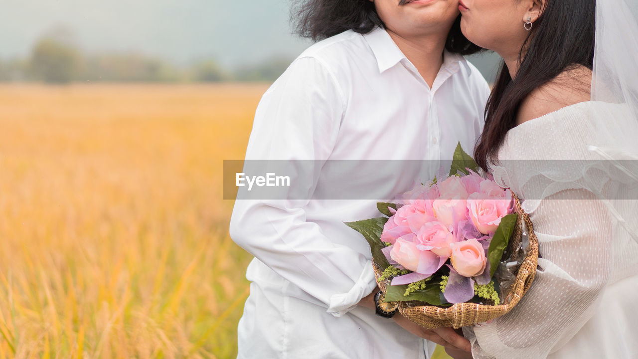 Midsection of woman holding flower bouquet on land
