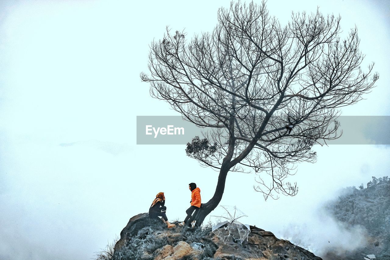 Men standing on rock against sky