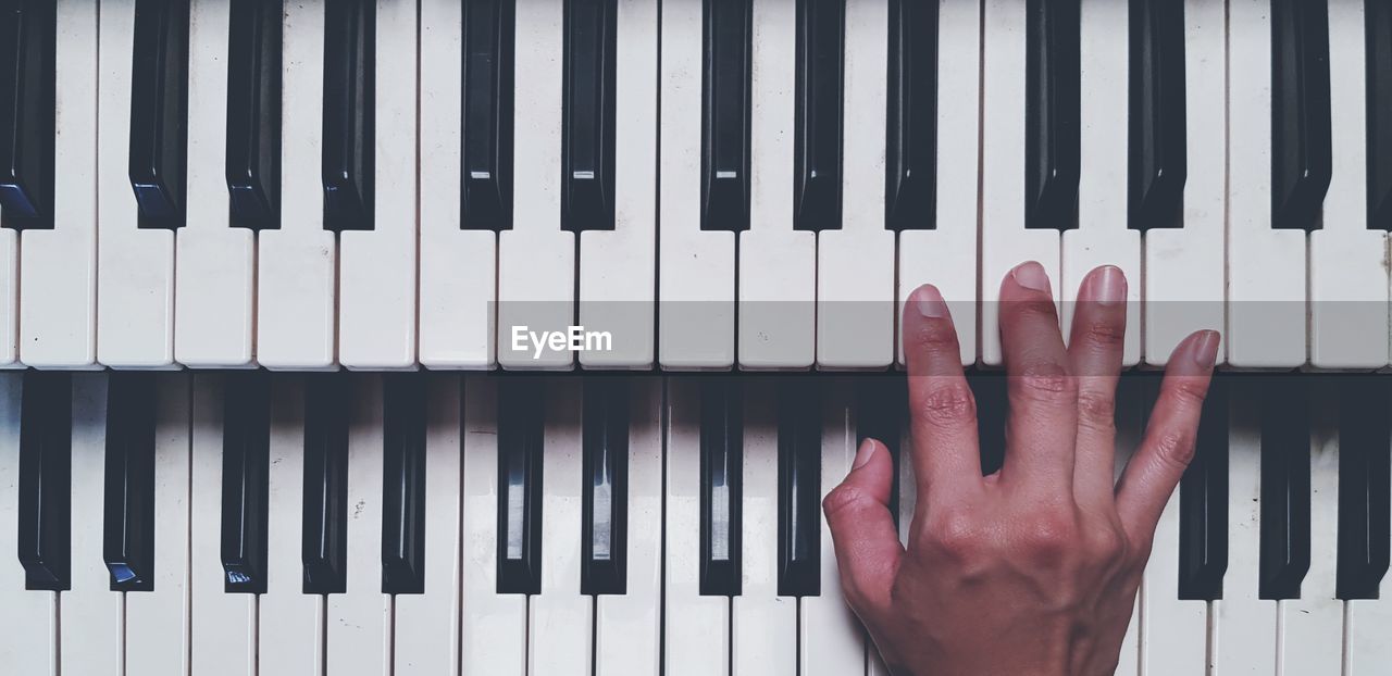 Close-up of cropped hand playing piano