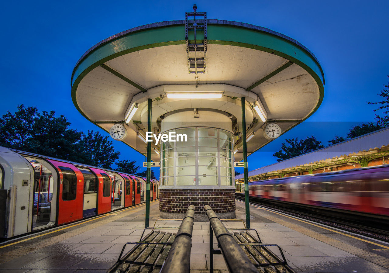 Evening at the urban train station with bright lights and passing trains