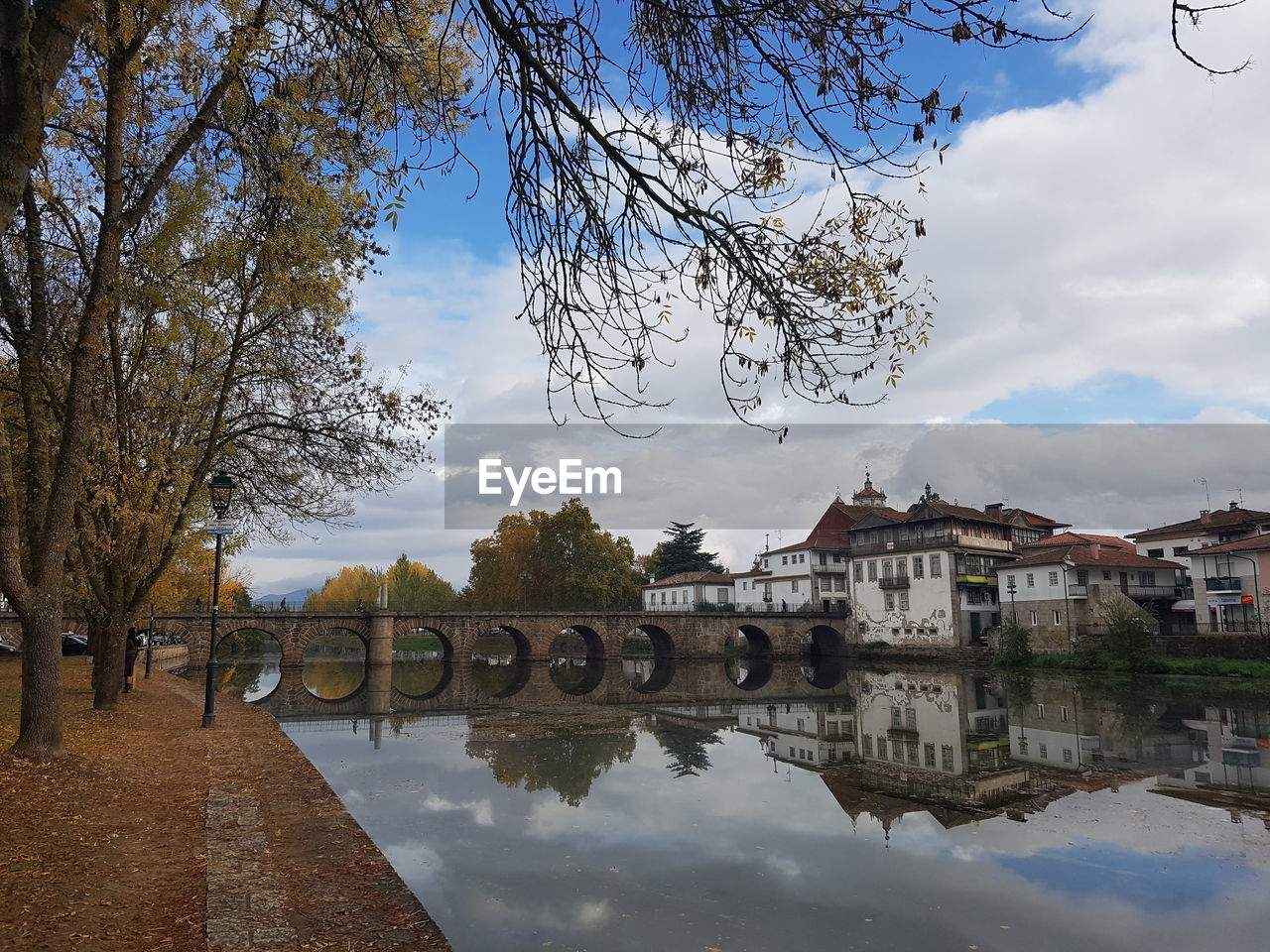 Arch bridge over river by buildings against sky