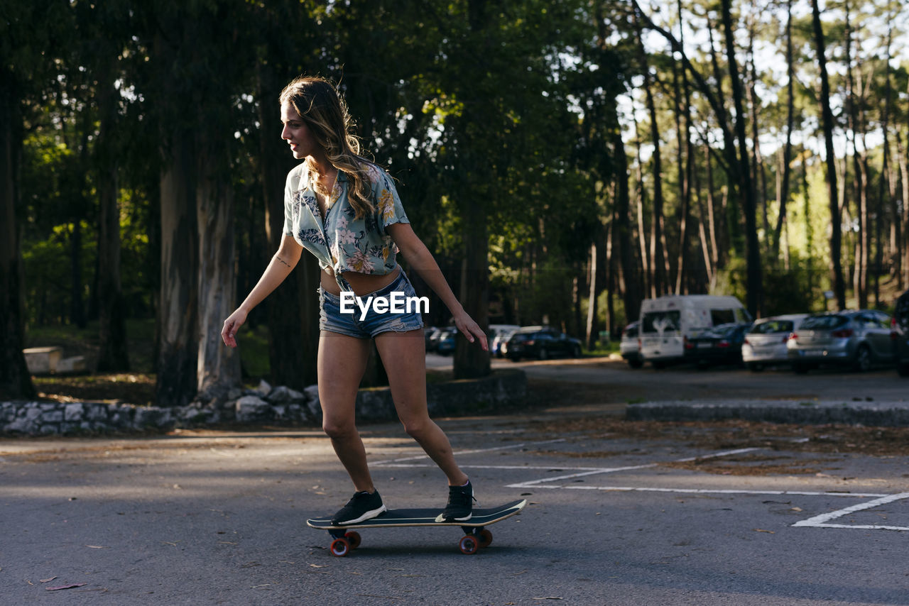 Beautiful skater practicing riding skate board on street near camping