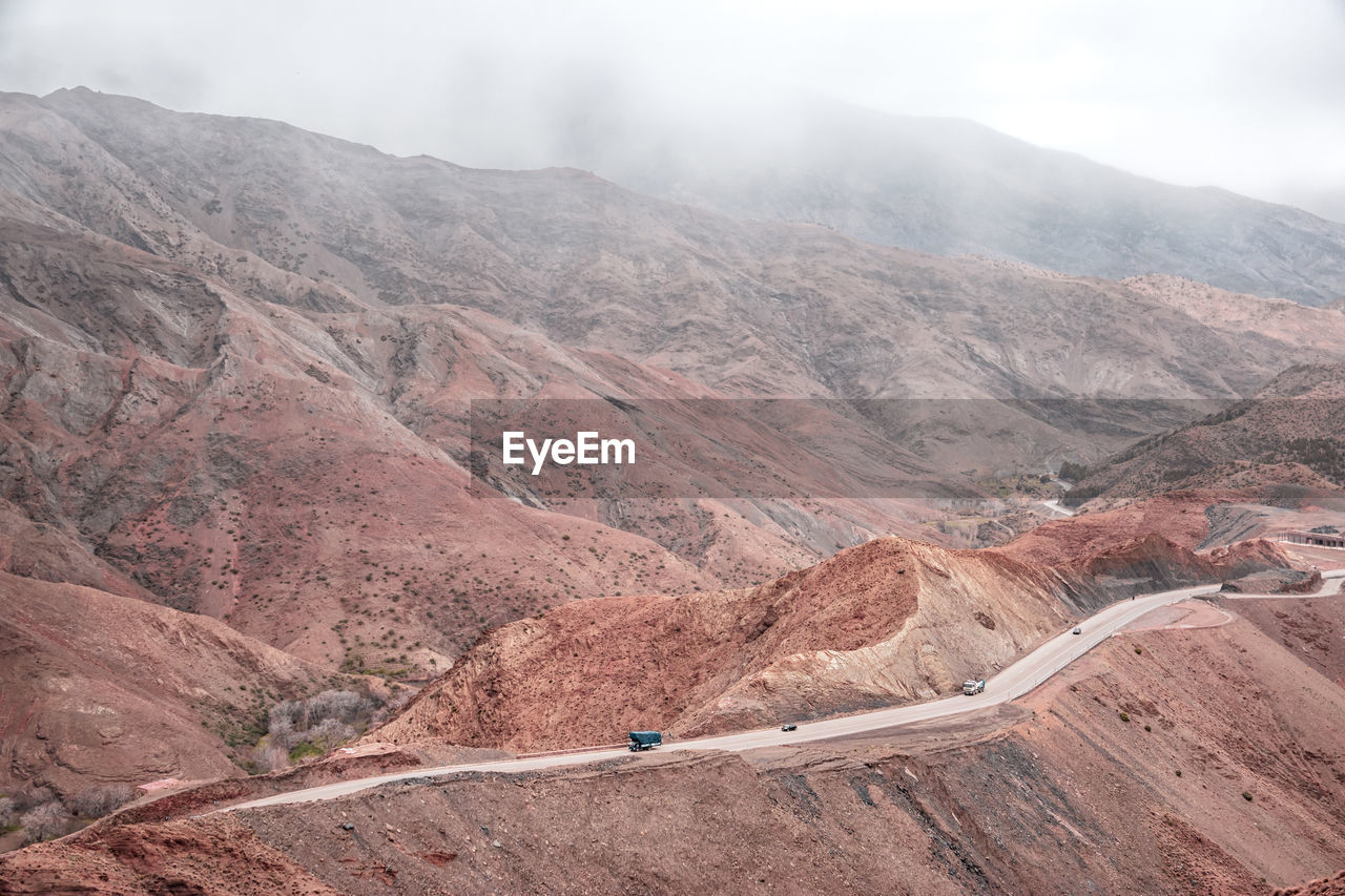 Scenic view of mountains against sky. a street with a fare cars in a misty fog