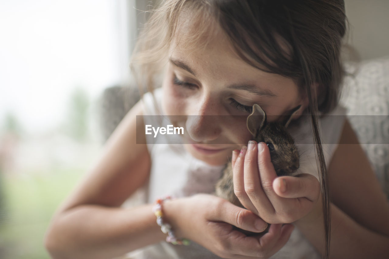 Close-up of girl holding bunny while sitting at home
