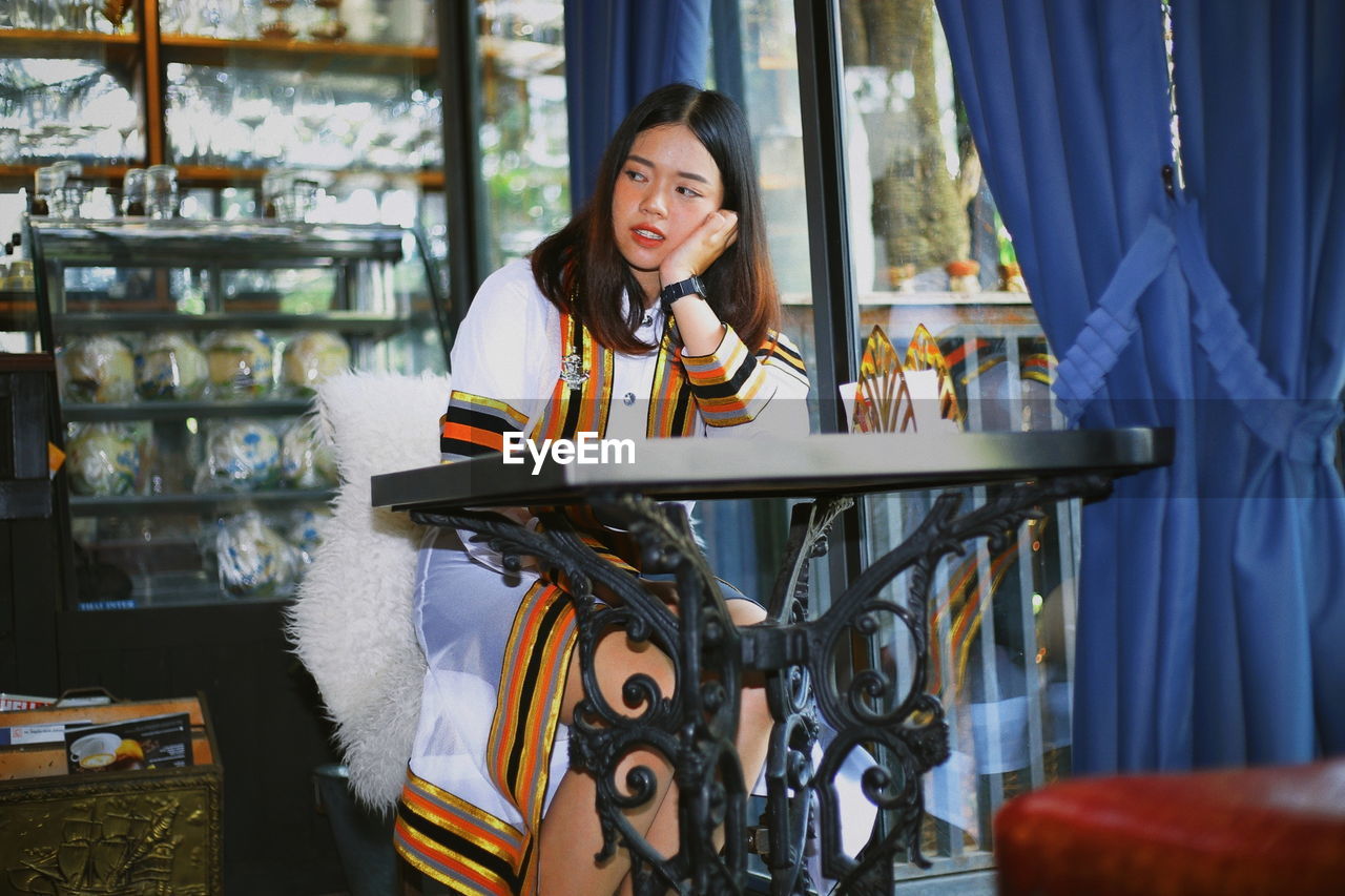 Thoughtful young woman sitting at table in restaurant