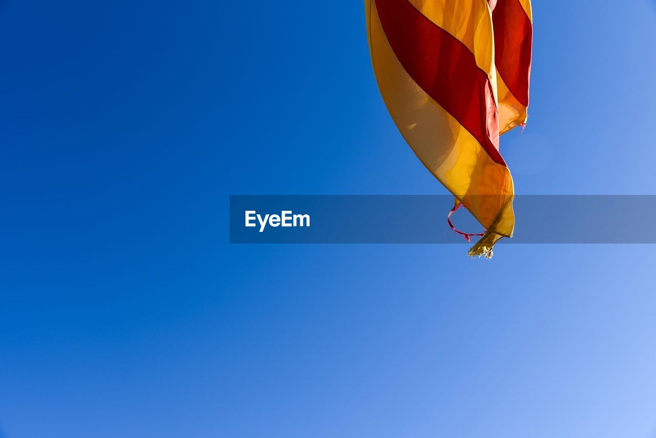 Low angle view of catalunya flag against clear blue sky