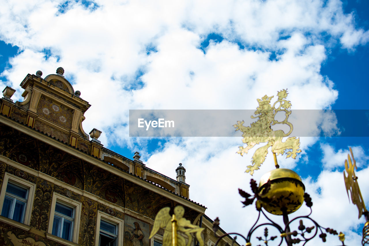 Low angle view of weather vane by building against sky