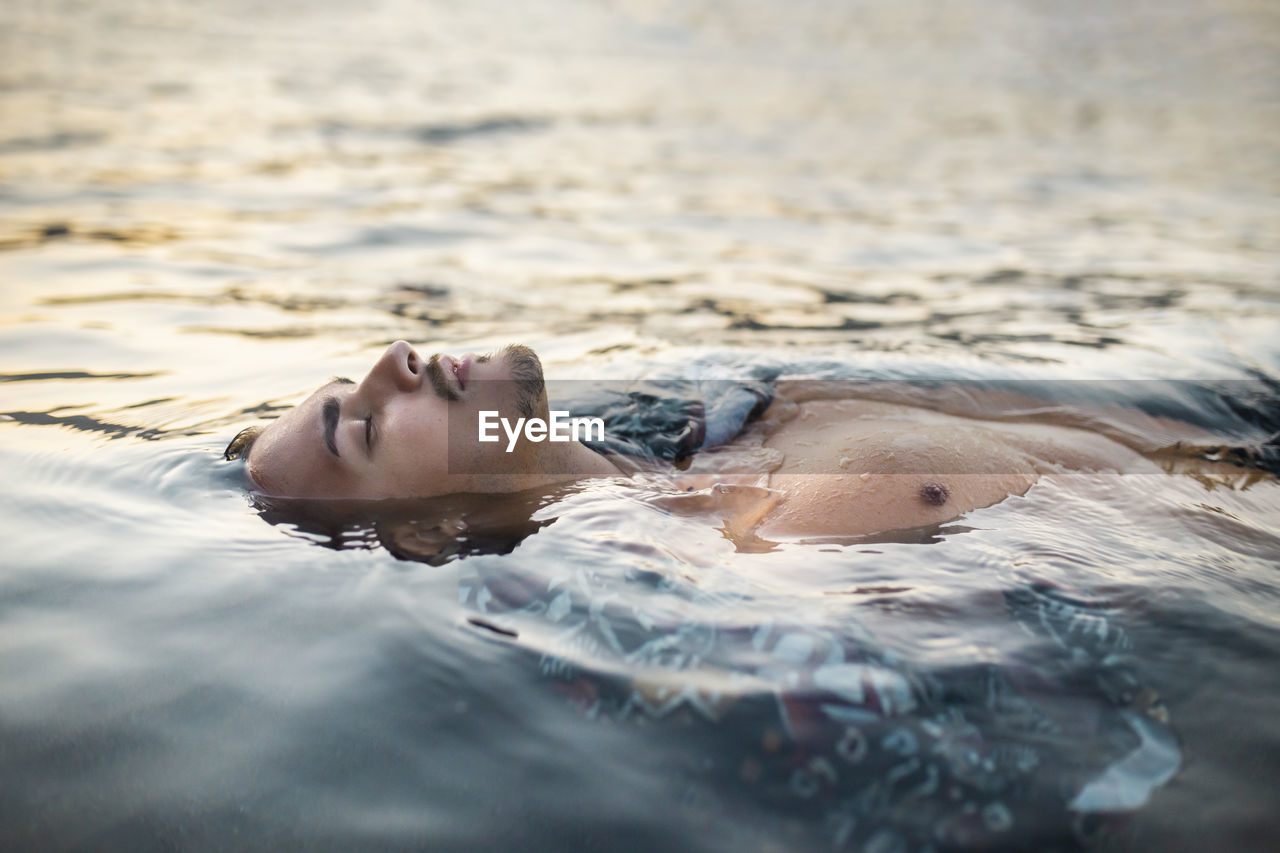 Young man with eyes closed floating in water