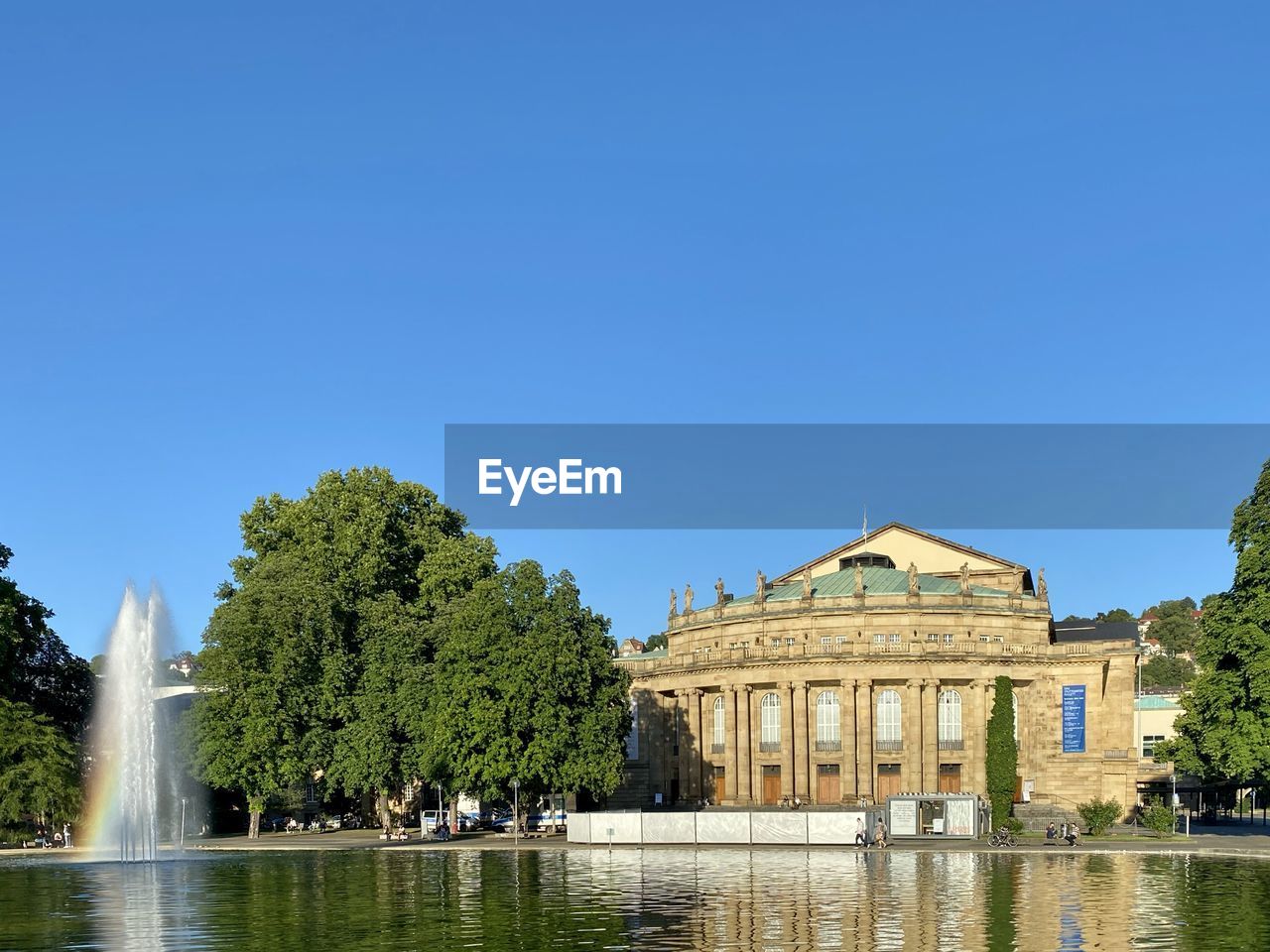 FOUNTAIN BY LAKE AND BUILDINGS AGAINST SKY