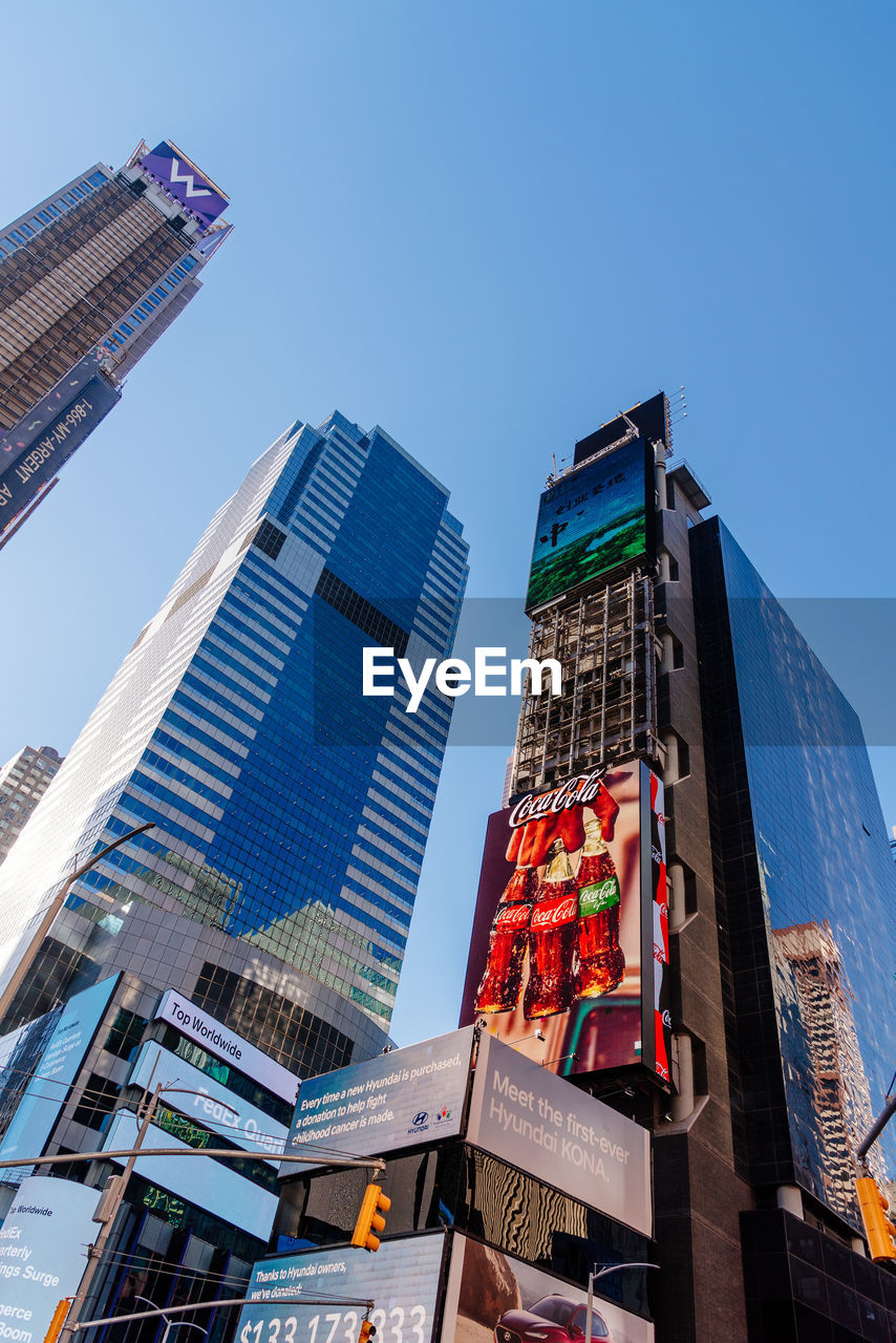 LOW ANGLE VIEW OF BUILDINGS IN CITY AGAINST CLEAR BLUE SKY