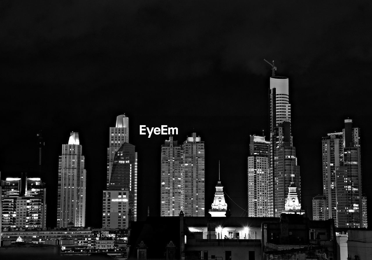 Illuminated buildings in city against sky at night