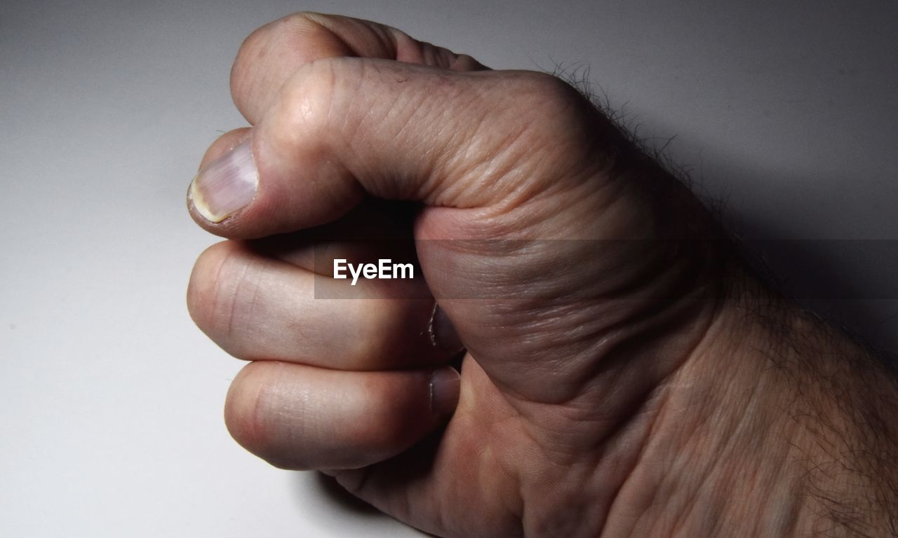 CLOSE-UP OF HUMAN HAND AGAINST WHITE BACKGROUND