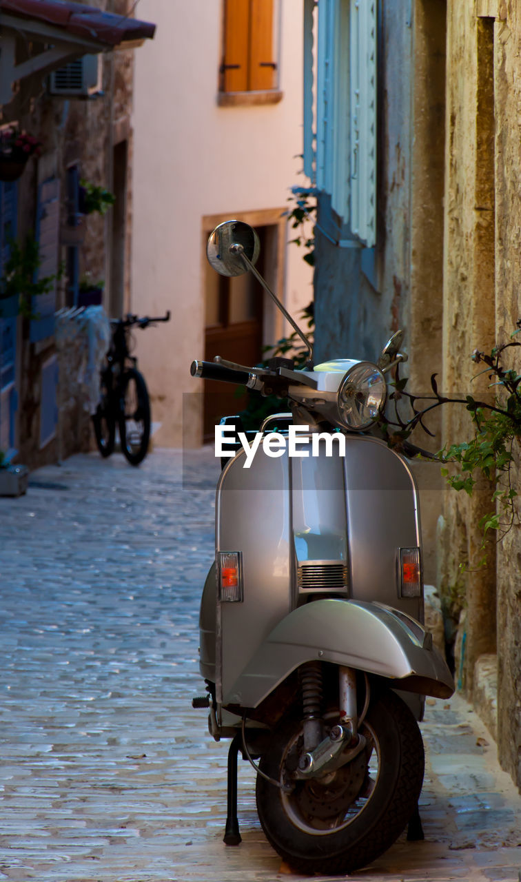 MOTORCYCLE PARKED ON STREET AMIDST BUILDINGS