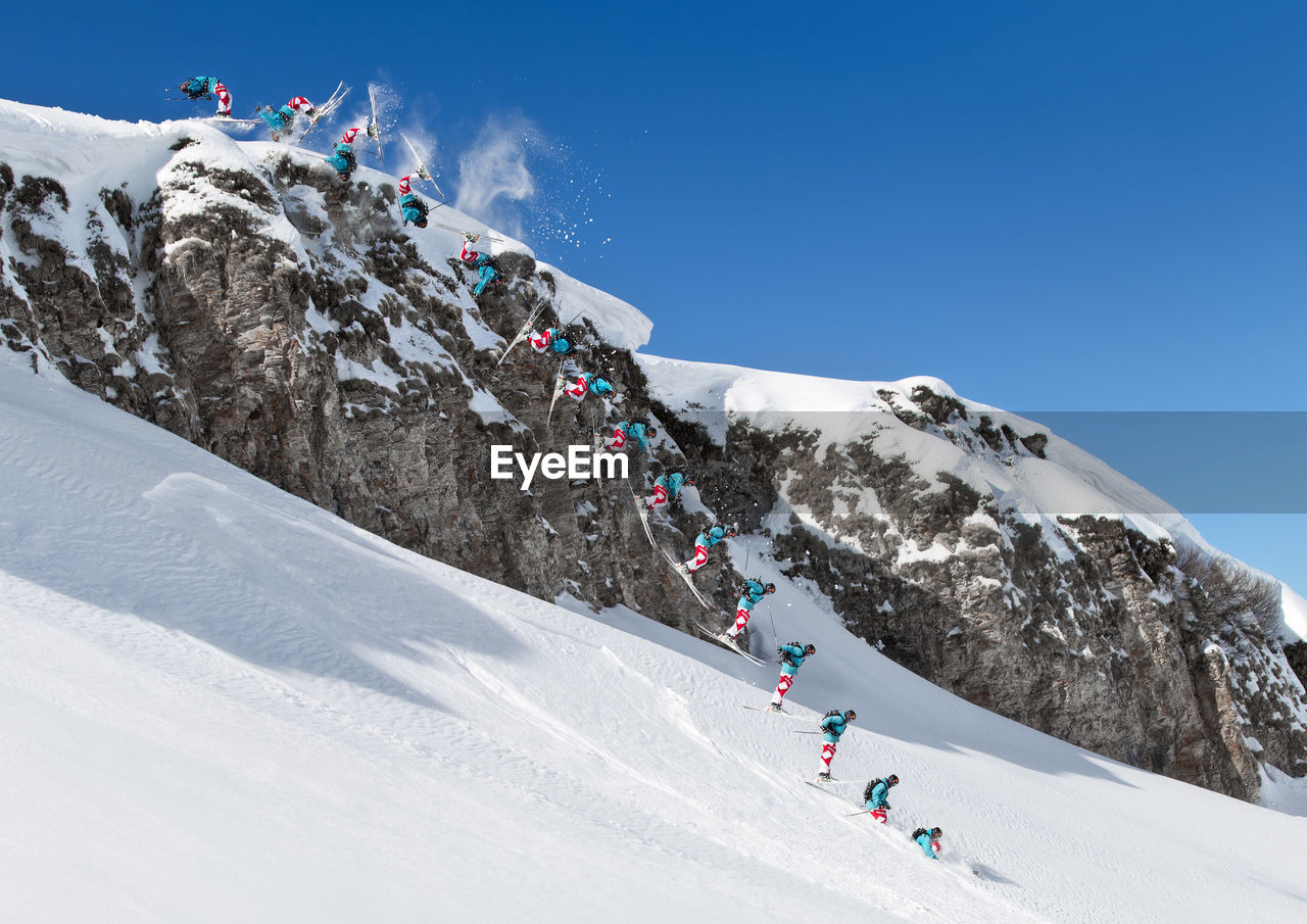 PEOPLE SKIING ON SNOWCAPPED MOUNTAIN AGAINST SKY