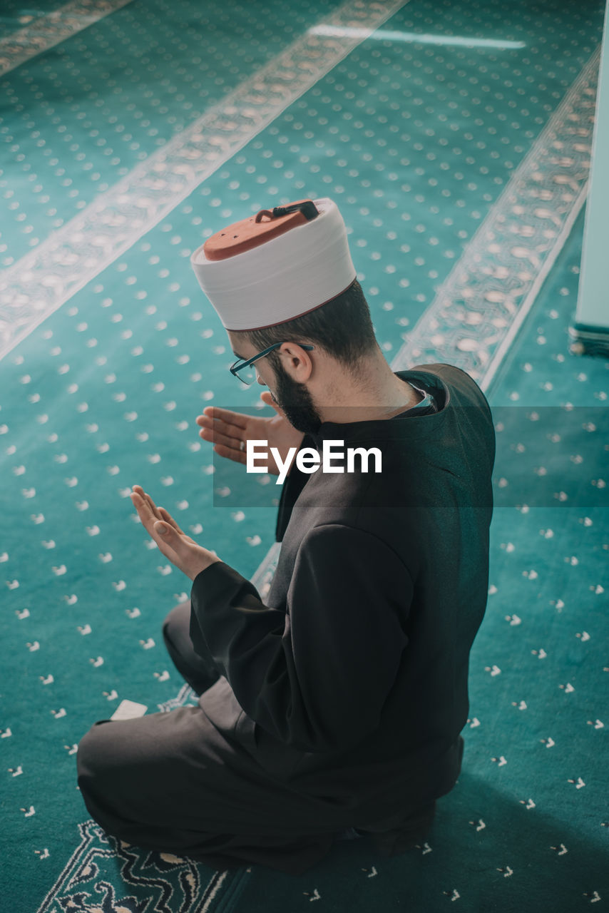 YOUNG MAN USING MOBILE PHONE WHILE SITTING ON LAPTOP