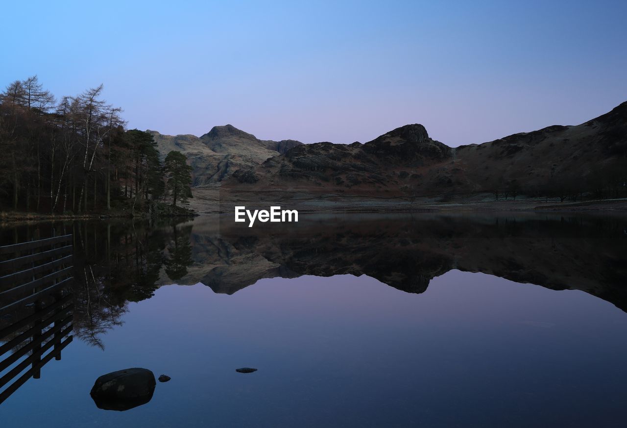 Scenic view of lake and mountains against clear blue sky