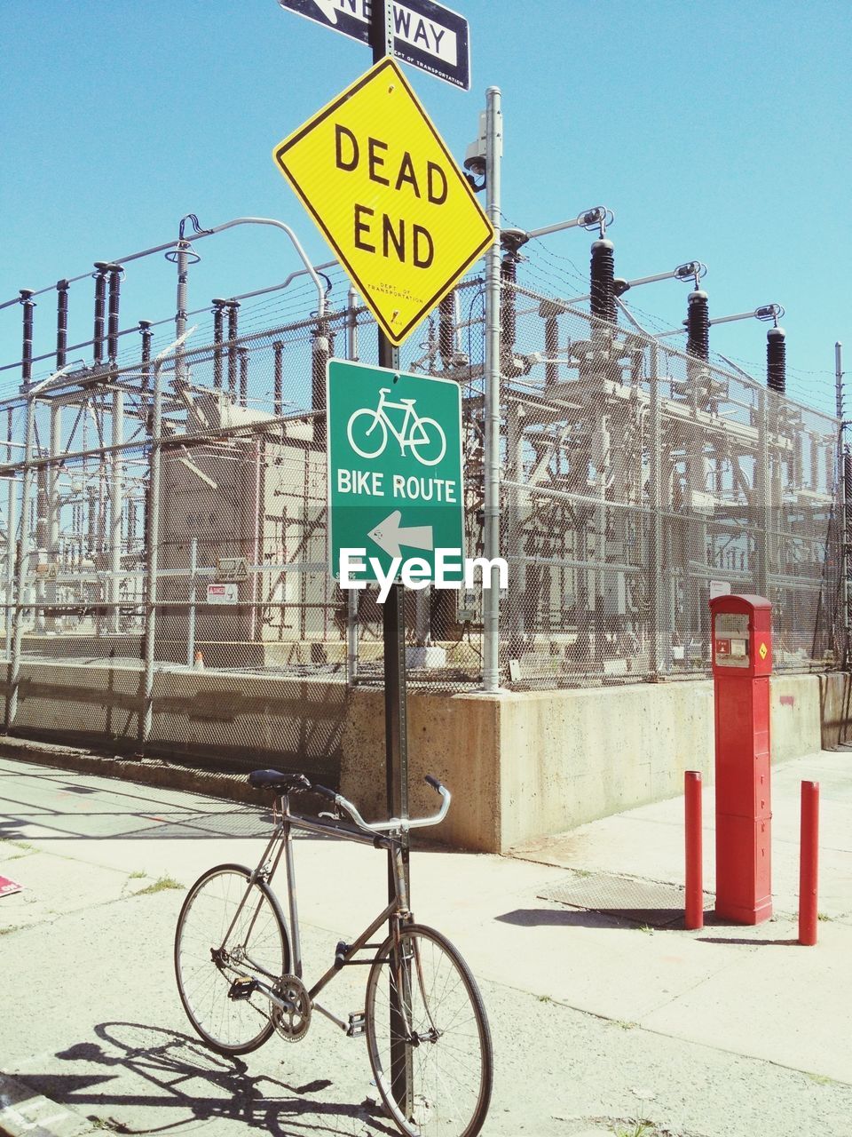 Bicycle parked by road sign pole