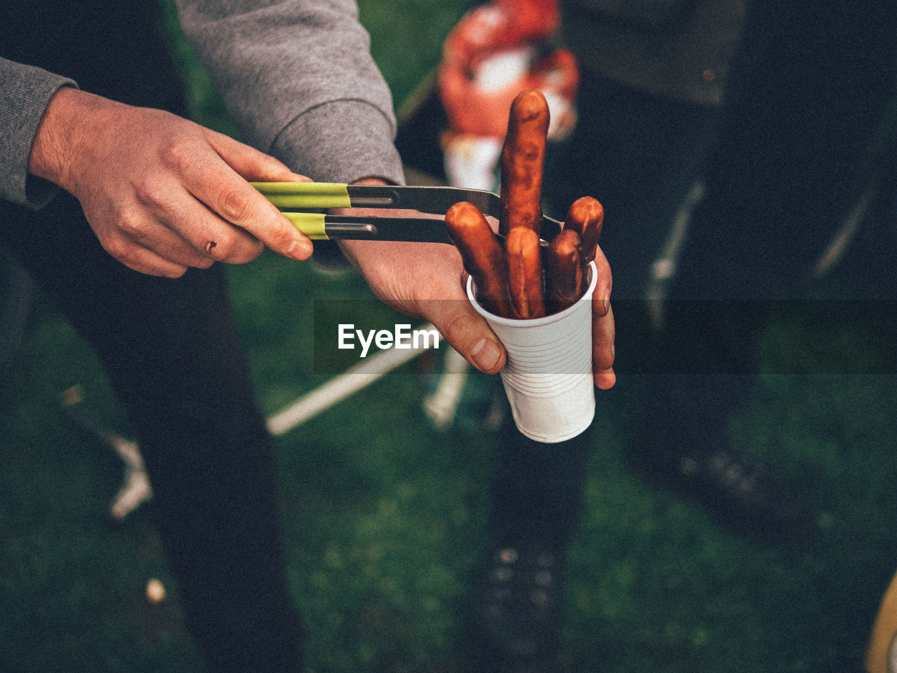 Close-up of man holding sausage in disposable cup