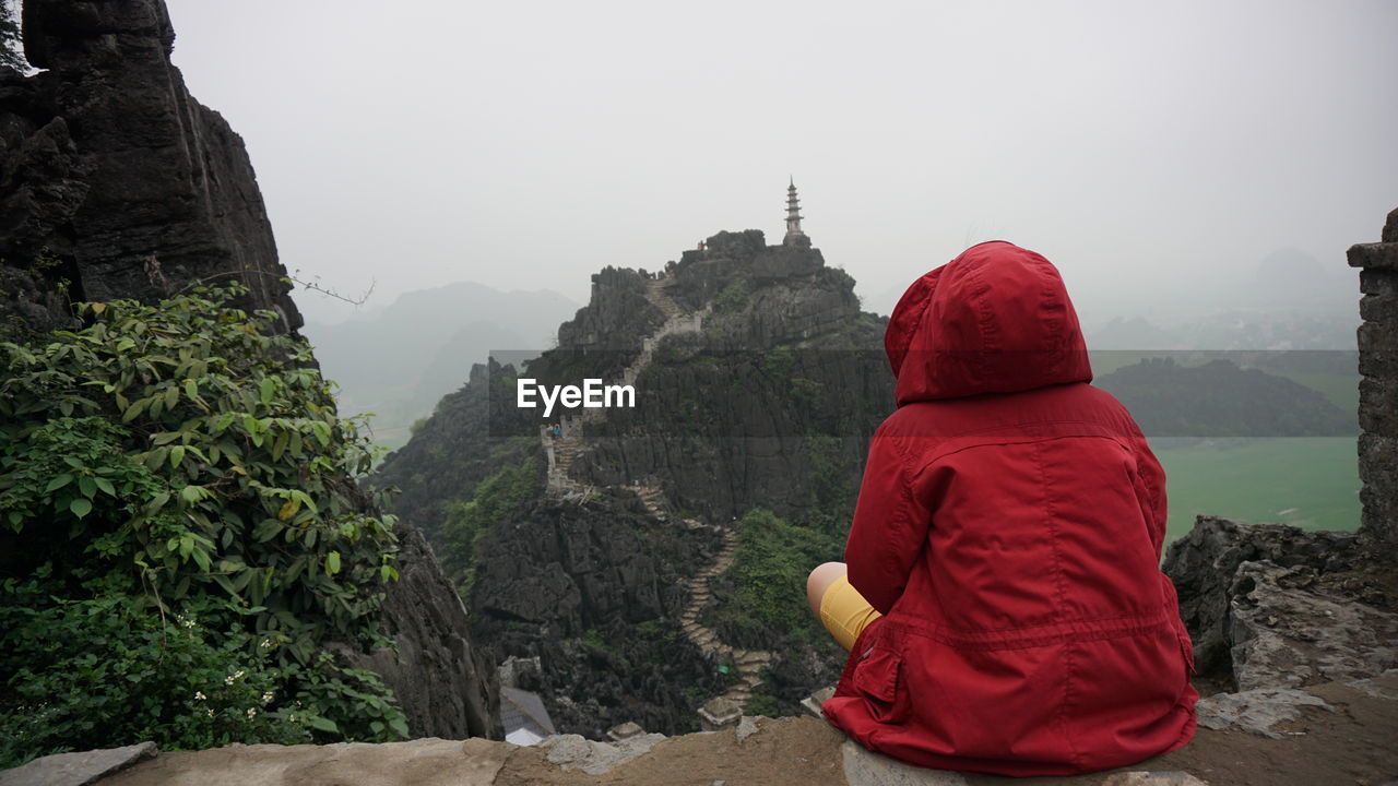 Rear view of man looking at mountain against sky