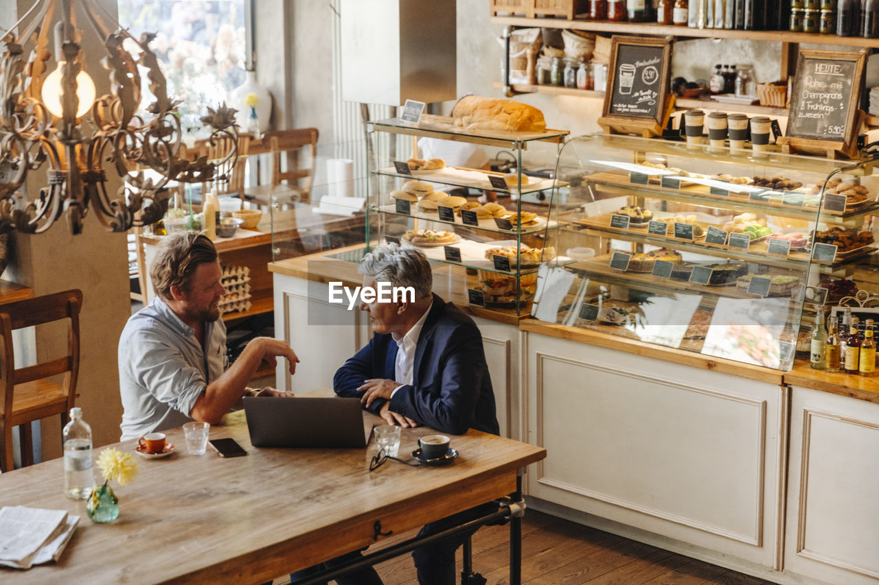 Two businessmen with laptop meeting in a cafe