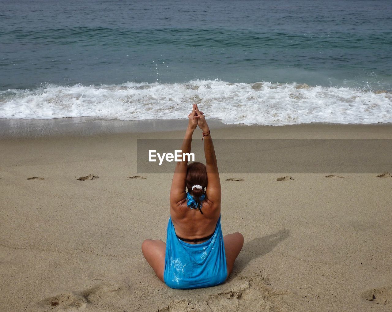 REAR VIEW OF YOUNG WOMAN IN SUNGLASSES ON BEACH