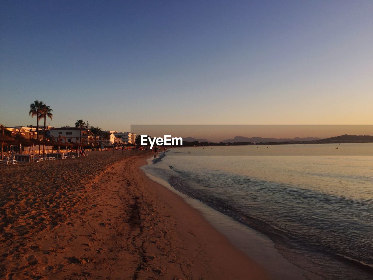 Scenic view of beach against clear sky at sunset