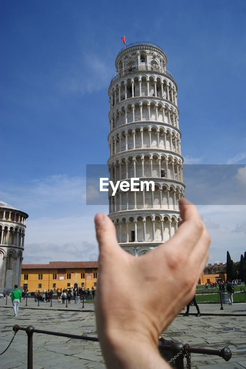 Optical illusion of cropped hand holding leaning tower of pisa