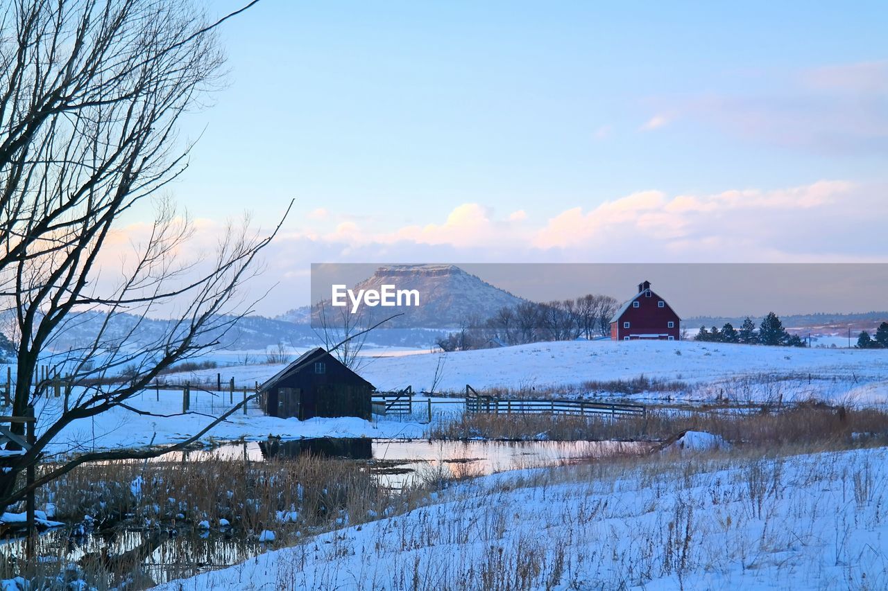 Houses on snow covered field against sky