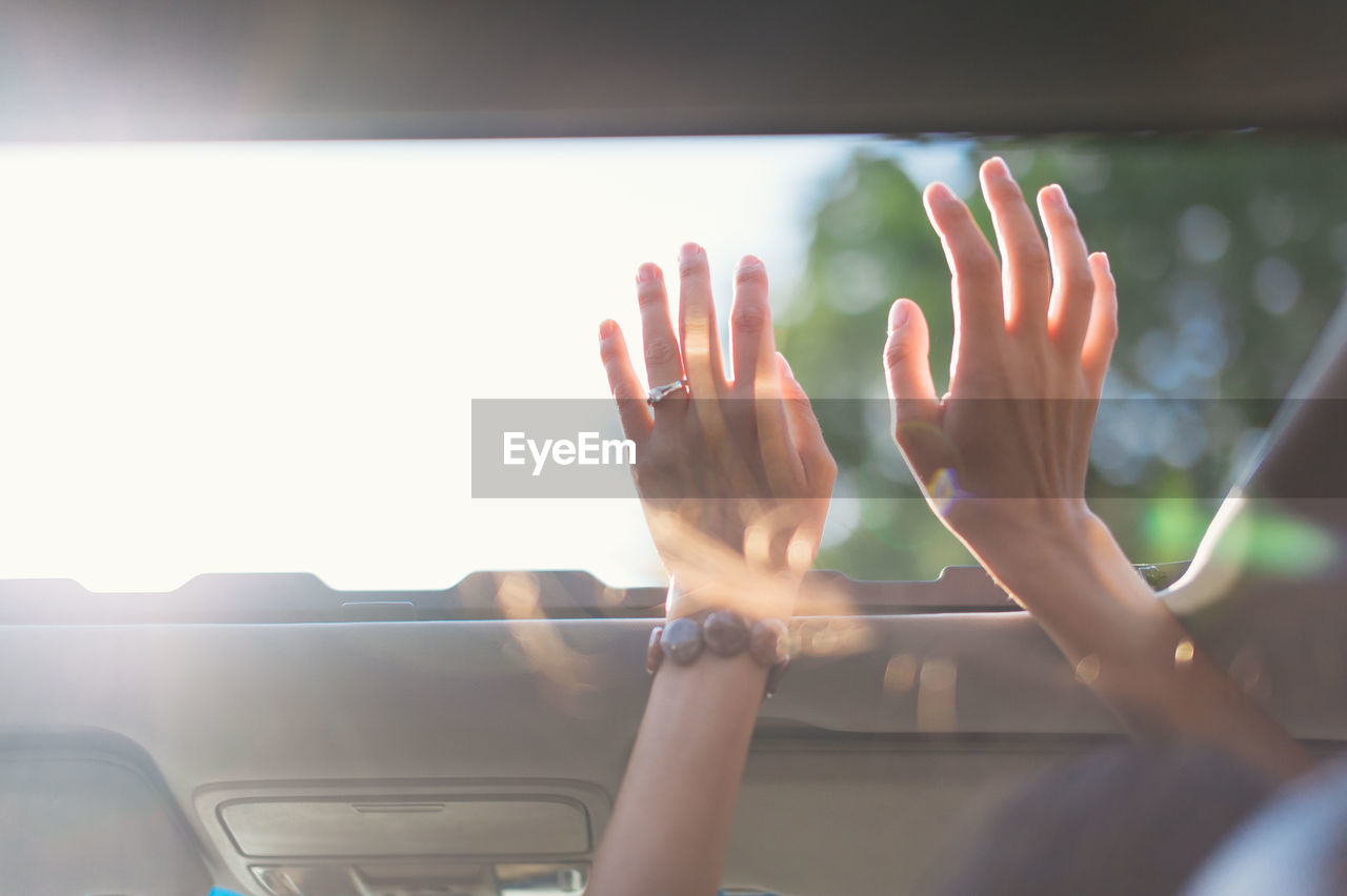 Cropped image of woman with arms raised in car